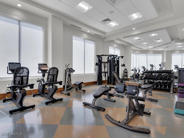 workout area featuring plenty of natural light, a paneled ceiling, and baseboards