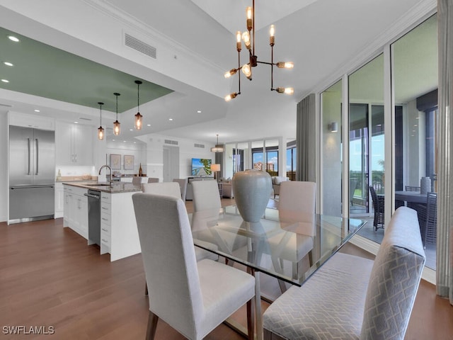 dining room featuring dark wood-style flooring, a chandelier, ornamental molding, and recessed lighting