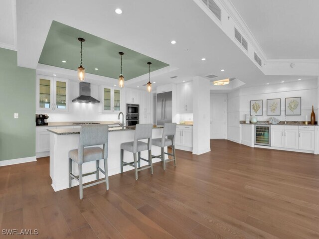 4800 Pelican Colony Blvd Unit 304, Bonita Springs, FL 34134 - kitchen with a raised ceiling, wall chimney exhaust hood, wine cooler, stainless steel appliances, and white cabinetry