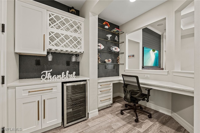 4424 Owens Way, Ave Maria, FL 34142 - indoor dry bar with wine cooler, light wood-type flooring, decorative backsplash, built in study area, and baseboards