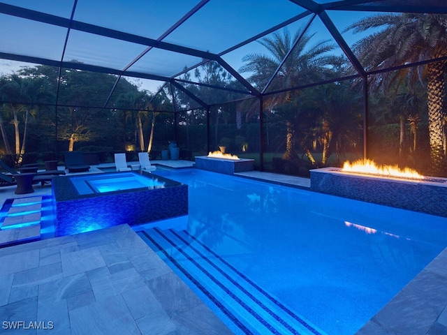 swimming pool with a fire pit, an in-ground hot tub, a patio area, and a lanai