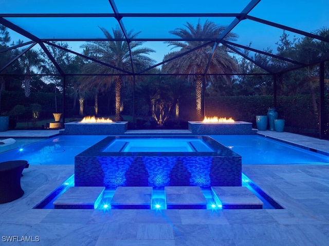outdoor pool with an in-ground hot tub, a fire pit, a patio, and glass enclosure