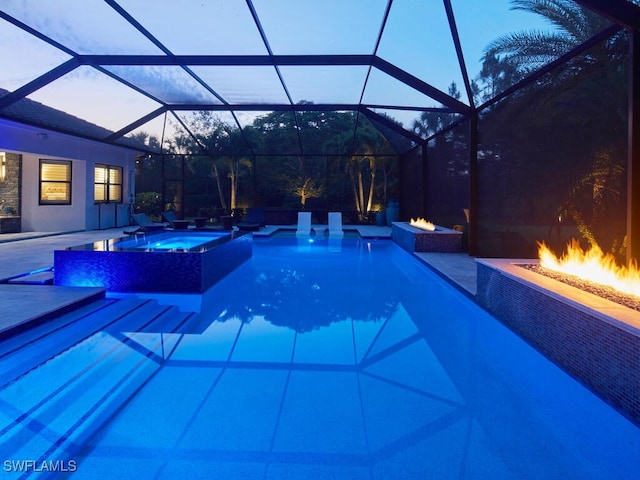 pool at dusk with an outdoor fire pit, a patio area, and a pool with connected hot tub