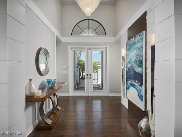 foyer featuring french doors, wood-type flooring, baseboards, and a towering ceiling
