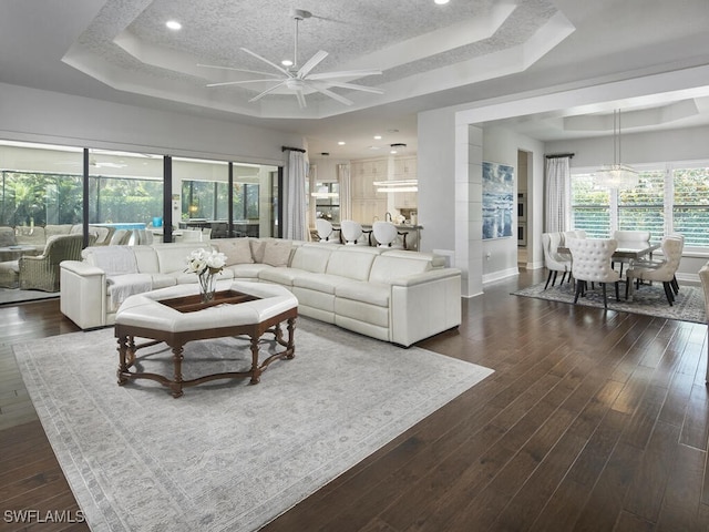 living area with a raised ceiling, ceiling fan, baseboards, dark wood-style floors, and recessed lighting