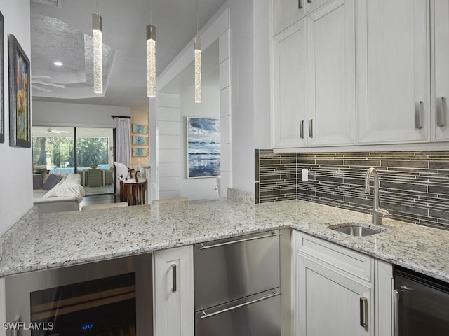 kitchen with wine cooler, a sink, decorative backsplash, white cabinets, and light stone countertops