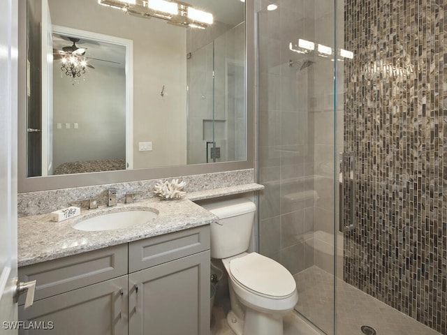 bathroom featuring a shower stall, toilet, vanity, and a ceiling fan