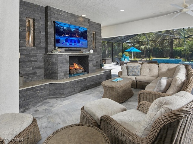 view of patio / terrace featuring an outdoor living space with a fireplace, a ceiling fan, and a lanai