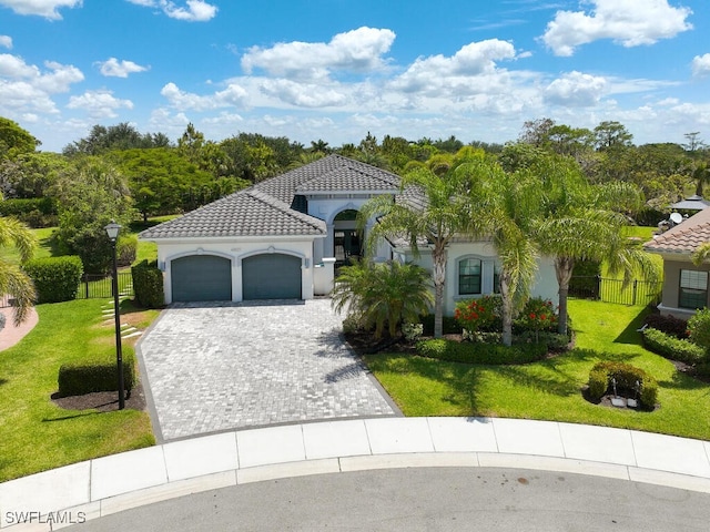 mediterranean / spanish-style house featuring an attached garage, stucco siding, decorative driveway, and a tile roof