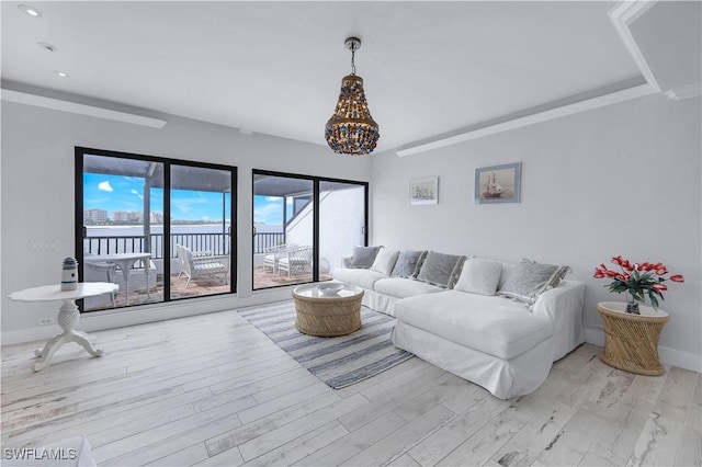 410 La Peninsula Blvd Unit 410, Naples, FL 34113 - living room featuring light wood-style floors, baseboards, an inviting chandelier, and a water view