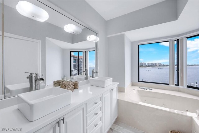 410 La Peninsula Blvd Unit 410, Naples, FL 34113 - full bath with double vanity, a jetted tub, and a water view