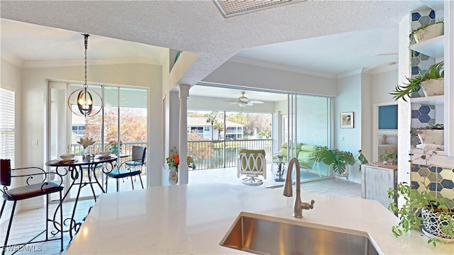 kitchen featuring crown molding, a sink, ceiling fan with notable chandelier, and wood finished floors