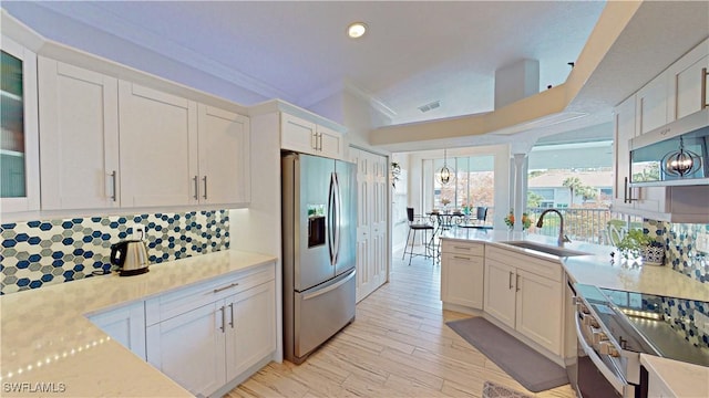 kitchen with backsplash, appliances with stainless steel finishes, a sink, light countertops, and white cabinetry
