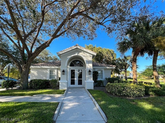 exterior space featuring a tiled roof, stucco siding, french doors, and a front yard