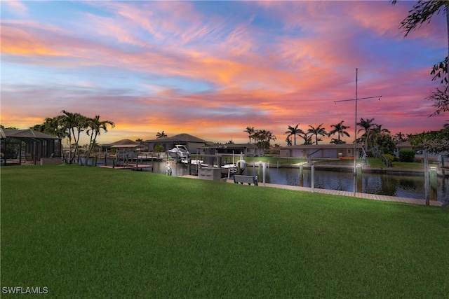 view of yard with boat lift, a water view, and a dock