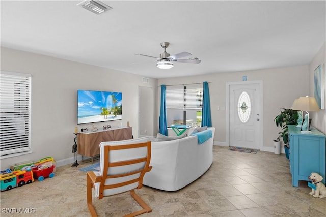living room featuring light tile patterned floors, baseboards, a ceiling fan, and visible vents