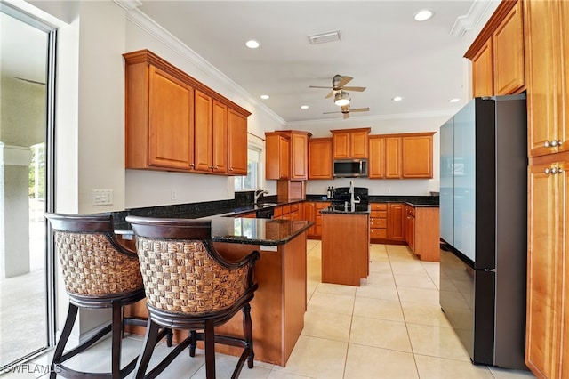 kitchen featuring crown molding, appliances with stainless steel finishes, a ceiling fan, a peninsula, and visible vents
