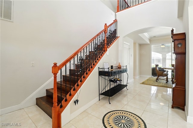 stairway with visible vents, crown molding, baseboards, ceiling fan, and arched walkways