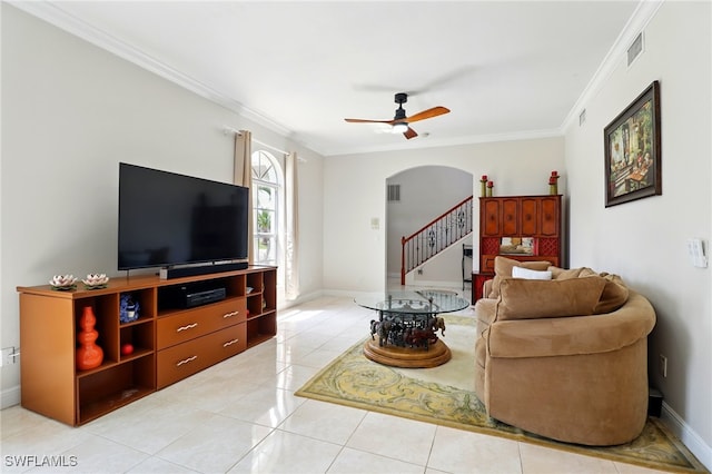 living room featuring crown molding, arched walkways, ceiling fan, and stairway