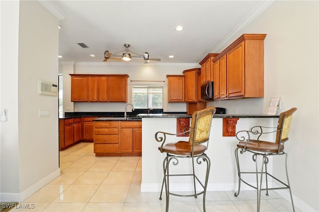 kitchen with brown cabinets, a peninsula, ornamental molding, a breakfast bar, and recessed lighting