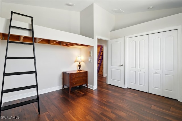 bedroom with visible vents, dark wood finished floors, baseboards, a closet, and lofted ceiling
