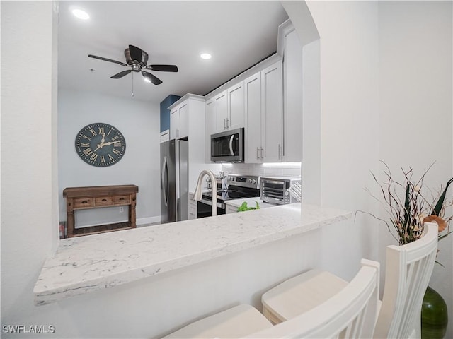 15780 Portofino Springs Blvd Unit 106, Fort Myers, FL 33908 - kitchen featuring light stone countertops, ceiling fan, arched walkways, stainless steel appliances, and decorative backsplash