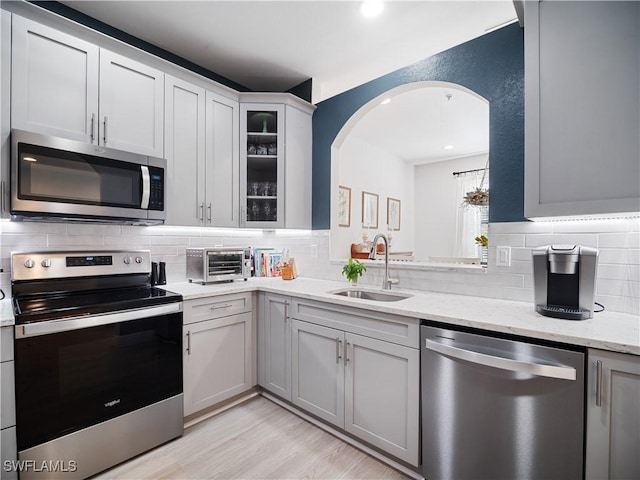 15780 Portofino Springs Blvd Unit 106, Fort Myers, FL 33908 - kitchen featuring a sink, arched walkways, stainless steel appliances, decorative backsplash, and a toaster