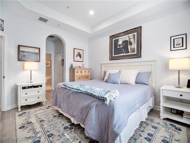 15780 Portofino Springs Blvd Unit 106, Fort Myers, FL 33908 - bedroom with visible vents, wood finished floors, baseboards, connected bathroom, and arched walkways