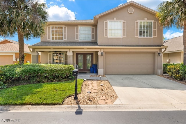 traditional-style house with a front lawn, stucco siding, french doors, concrete driveway, and an attached garage