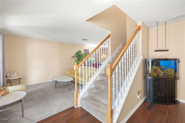 stairway with baseboards, visible vents, and wood finished floors