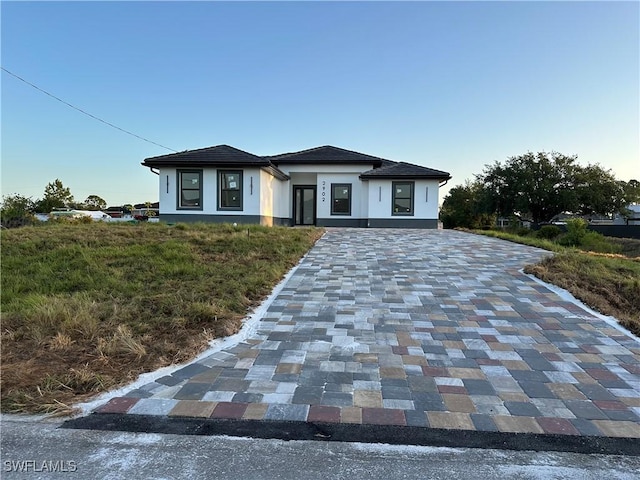 prairie-style home featuring stucco siding and decorative driveway