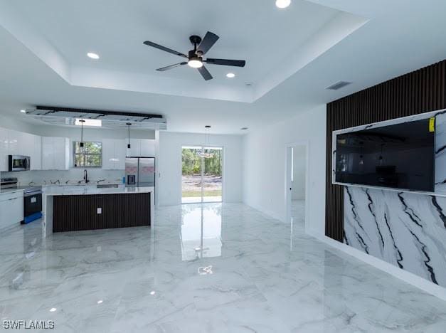 living room with visible vents, plenty of natural light, a raised ceiling, and ceiling fan