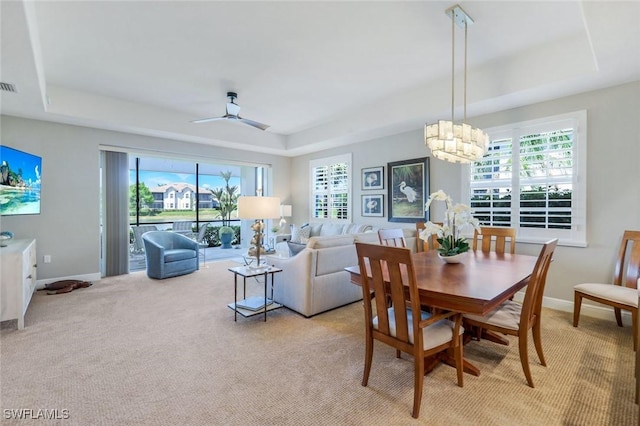 dining area featuring light carpet, a tray ceiling, and a wealth of natural light