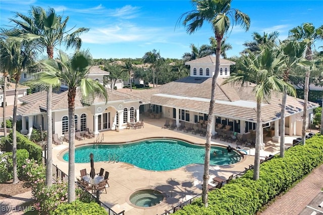 community pool with french doors, a patio, and a hot tub