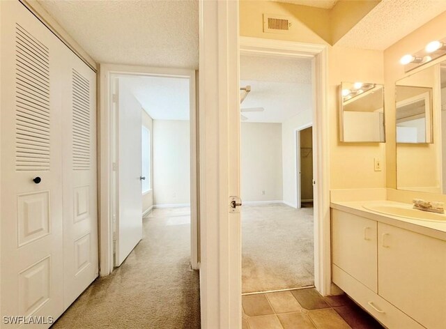 13515 Eagle Ridge Dr Unit 522, Fort Myers, FL 33912 - hall with visible vents, a sink, a textured ceiling, and light carpet