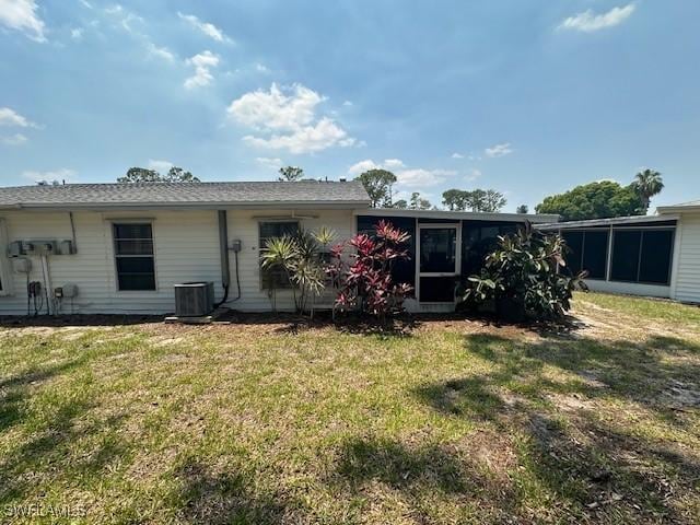 back of property with a sunroom, central AC, and a yard