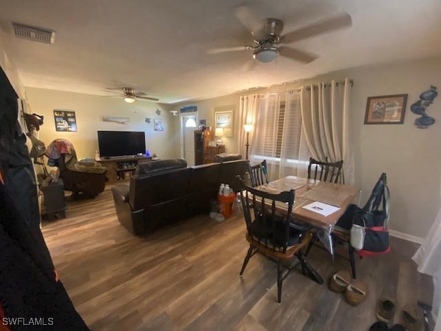 dining space featuring visible vents, baseboards, ceiling fan, and wood finished floors