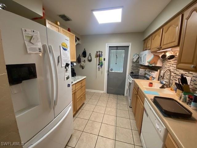 kitchen featuring a sink, white appliances, light countertops, light tile patterned floors, and visible vents
