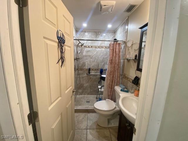 bathroom featuring tile patterned flooring, vanity, toilet, visible vents, and a stall shower