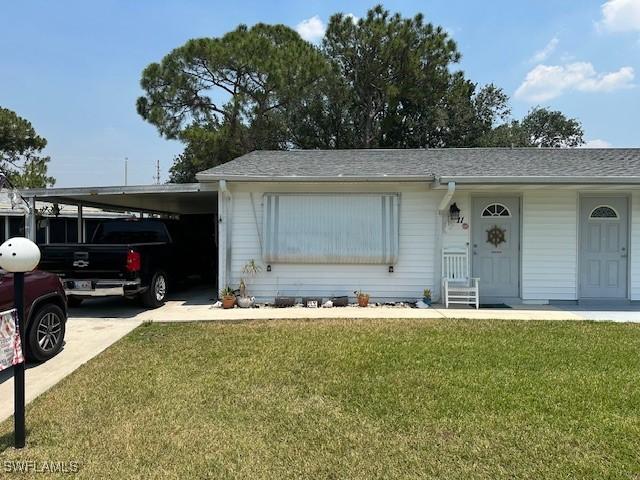 ranch-style home featuring a front lawn, driveway, and a carport