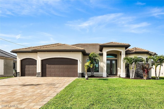 mediterranean / spanish-style house featuring a garage, a front lawn, decorative driveway, stucco siding, and french doors