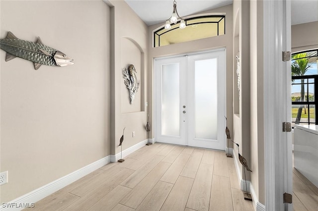 foyer featuring french doors, baseboards, and light wood-type flooring