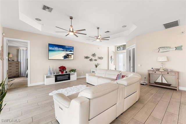 living area featuring a raised ceiling, wood tiled floor, and visible vents