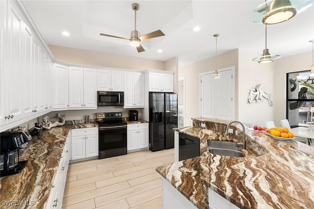 kitchen featuring wood tiled floor, a sink, black appliances, dark stone countertops, and white cabinetry