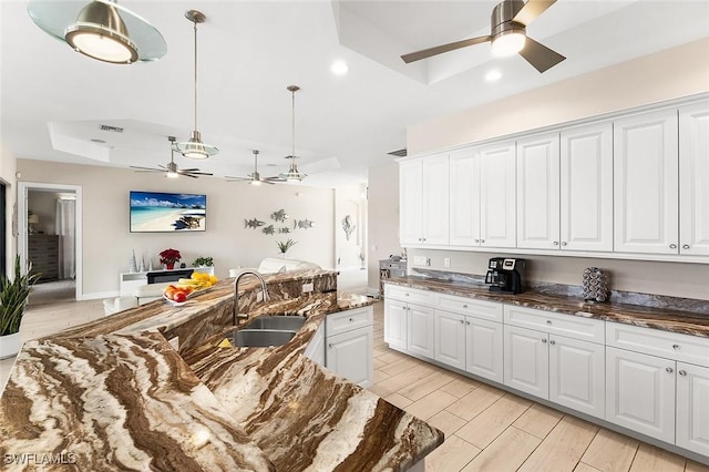 kitchen featuring white cabinetry, ceiling fan, and a sink