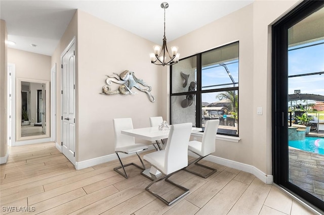 dining space featuring light wood-style floors, baseboards, and an inviting chandelier