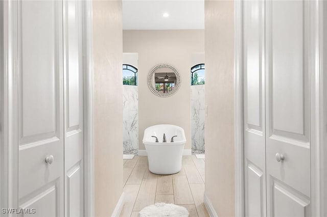 bathroom featuring a closet, baseboards, and a soaking tub
