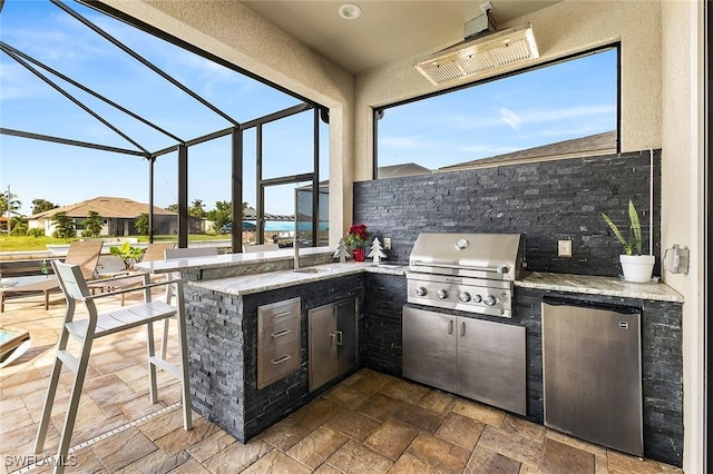 view of patio / terrace featuring a sink, grilling area, an outdoor kitchen, outdoor wet bar, and a lanai