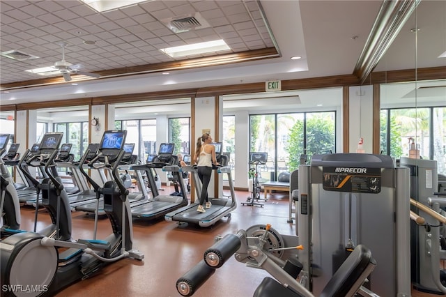 gym with visible vents, a raised ceiling, and ceiling fan