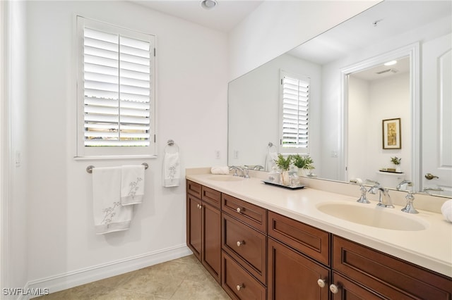 full bath with a sink, baseboards, tile patterned flooring, and double vanity